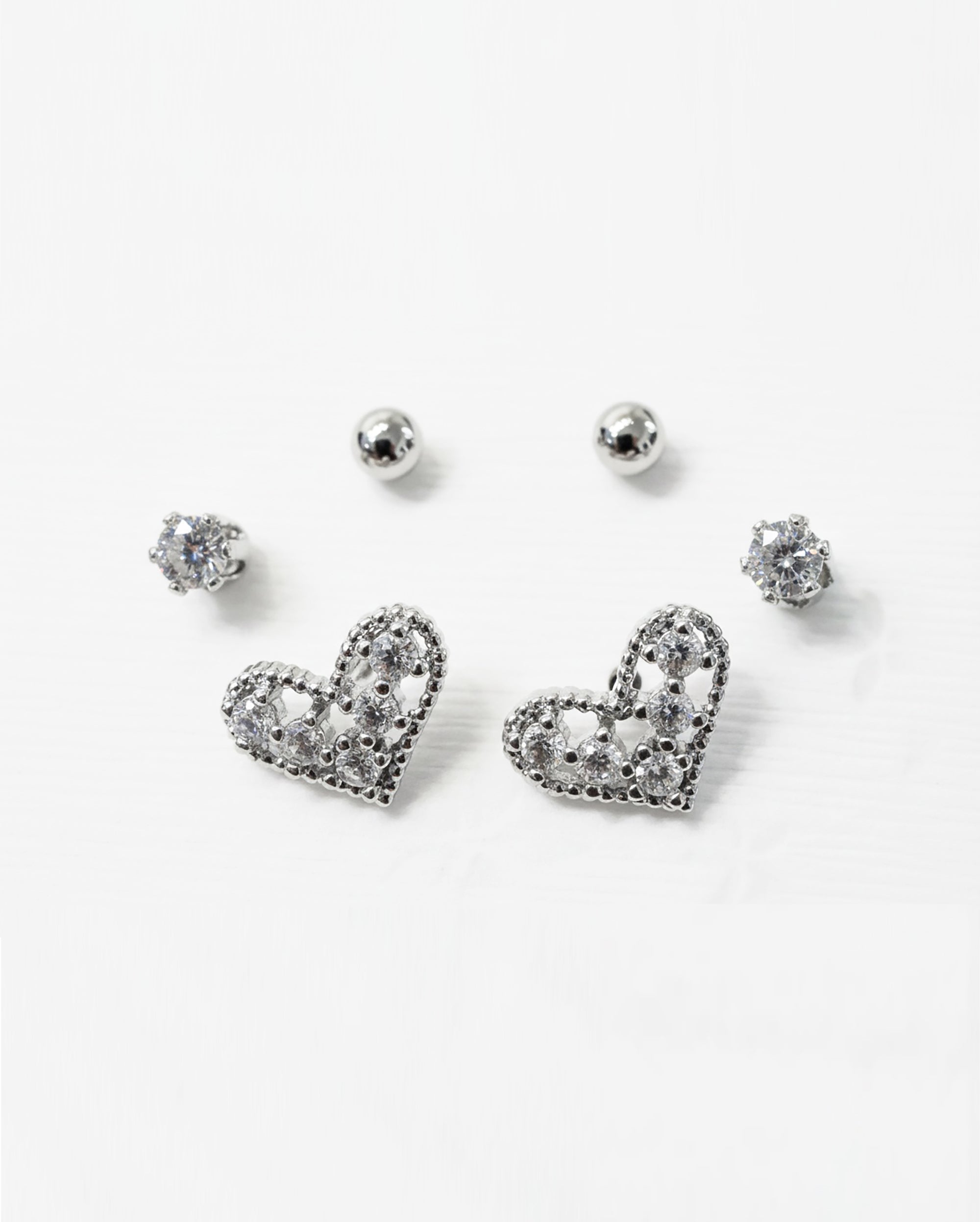 Set of silver heart-shaped earrings on a white background